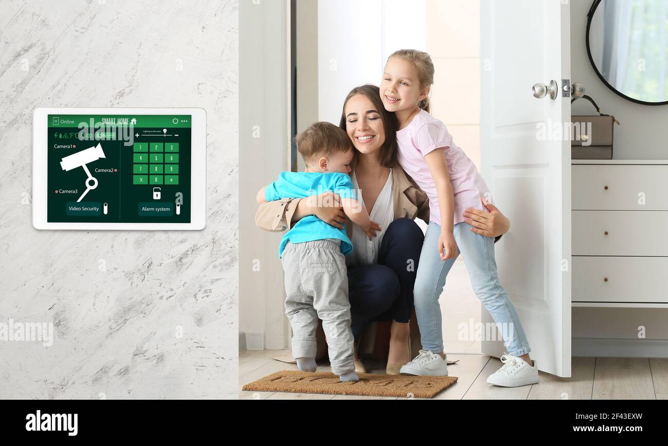 Happy children and their mother in hall under protection of smart home