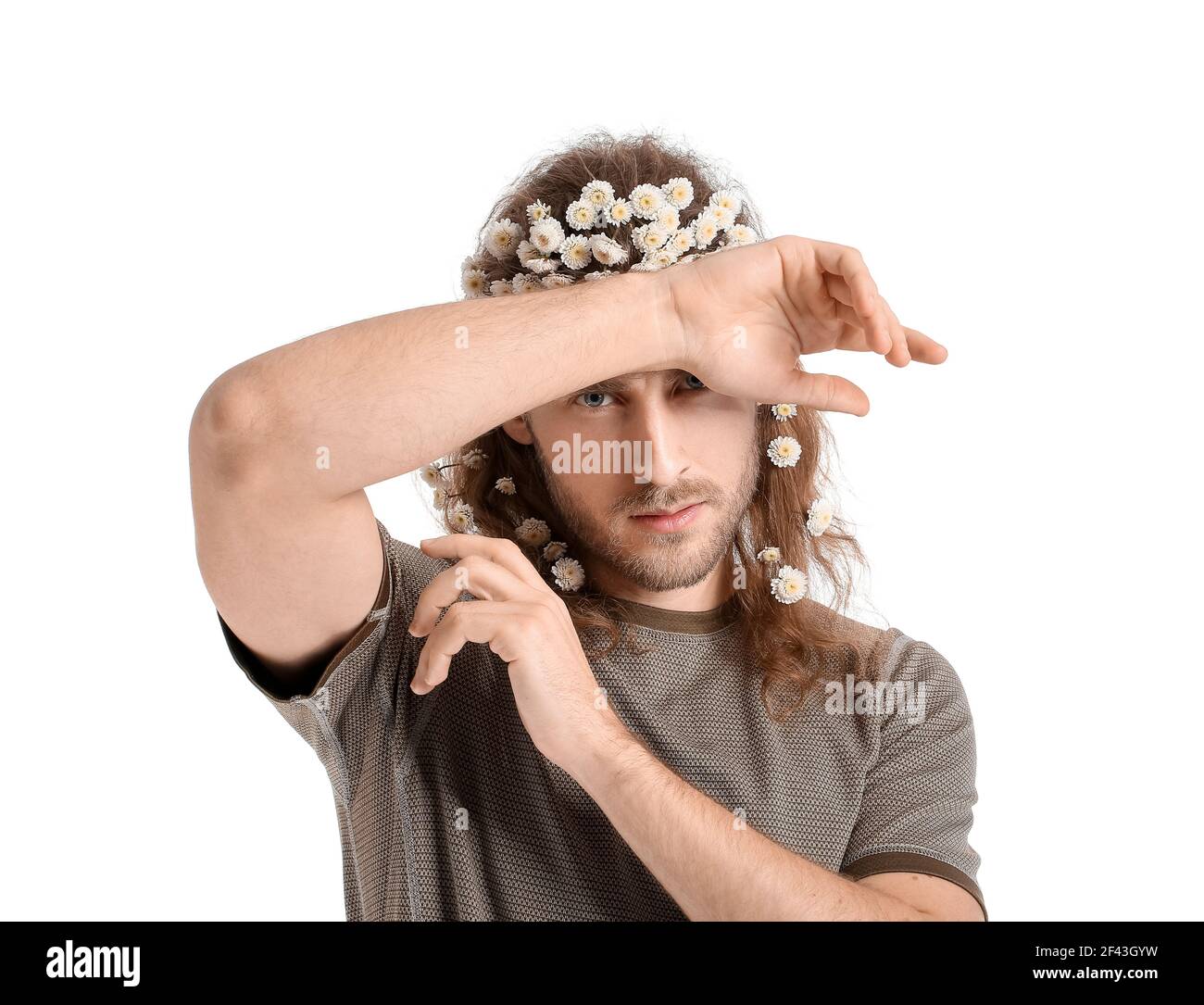 Portrait of handsome young man with flowers in hair on white background ...