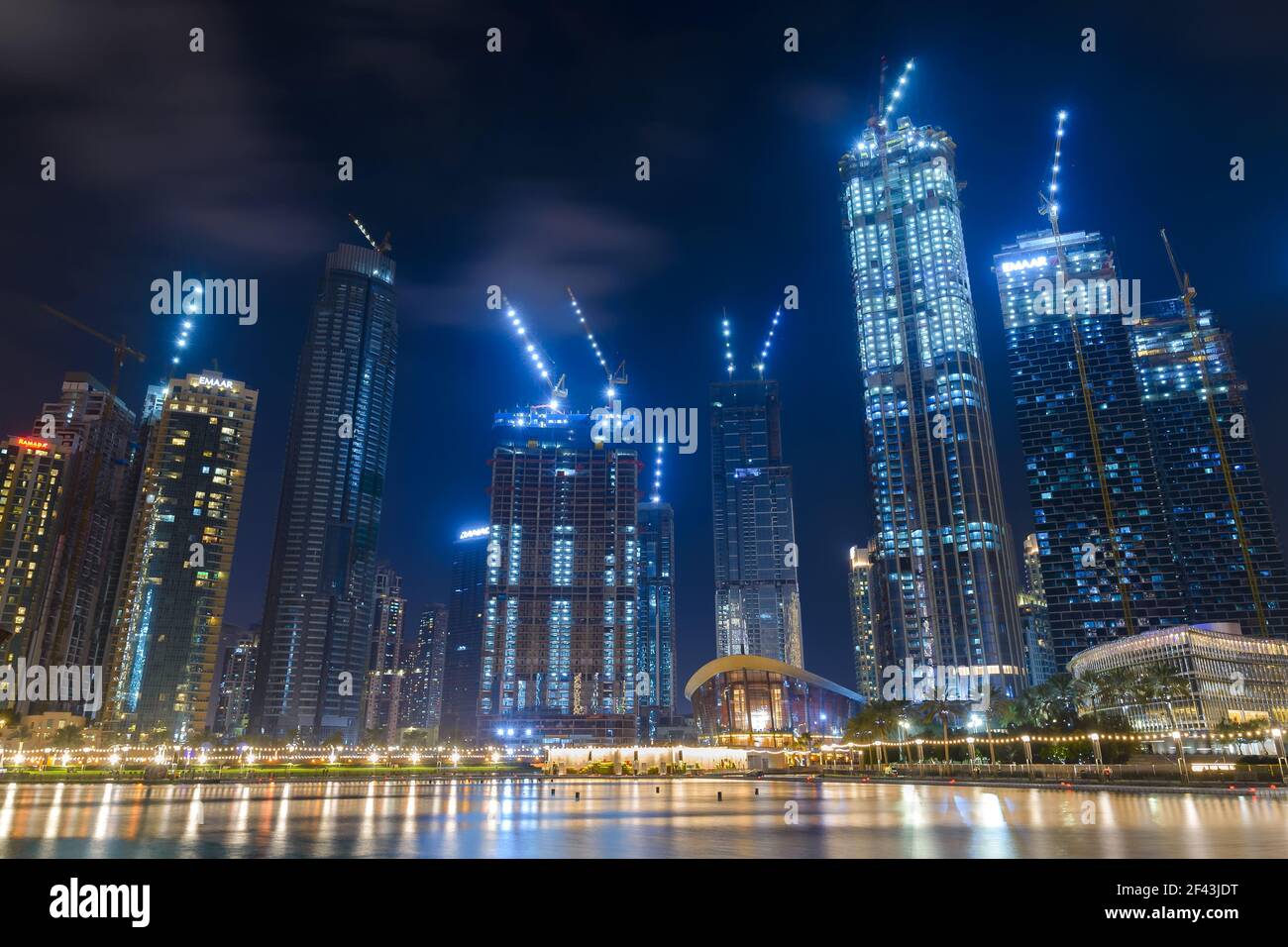 Multiple buildings with cranes at night near Dubai Mall in United Arab Emirates. Buildin construction cranes illuminated. Stock Photo