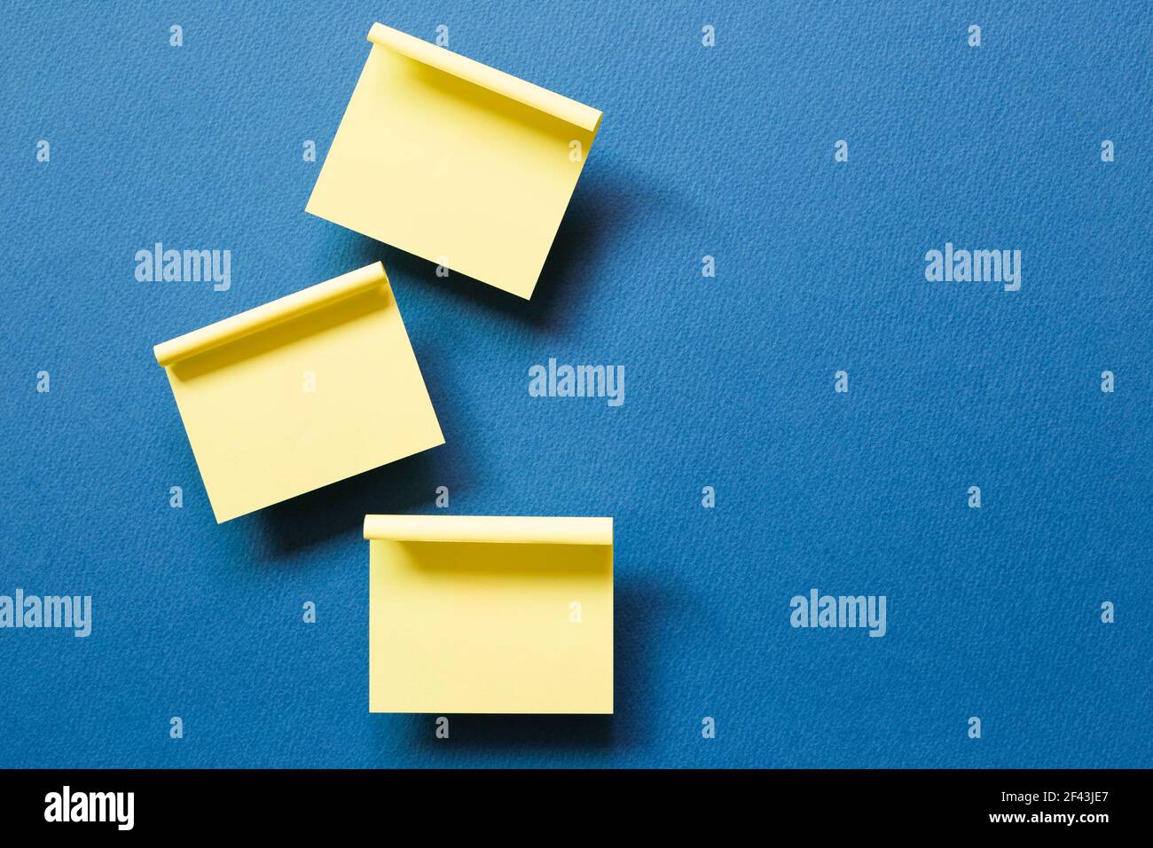 Yellow memo pad sticky note on blue background. top view, copy space