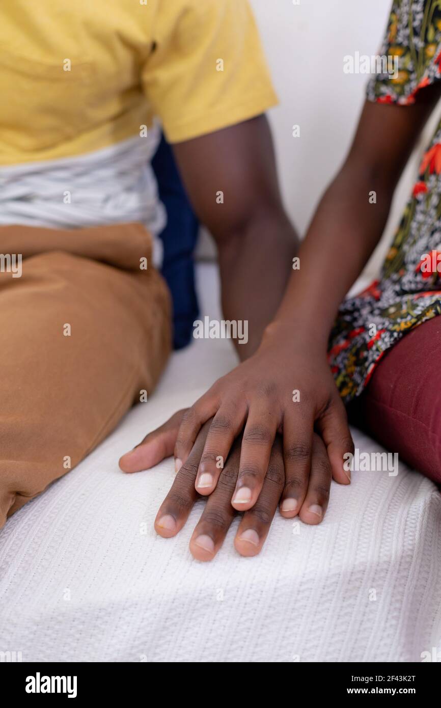African american couple sitting on sofa holding hands Stock Photo - Alamy