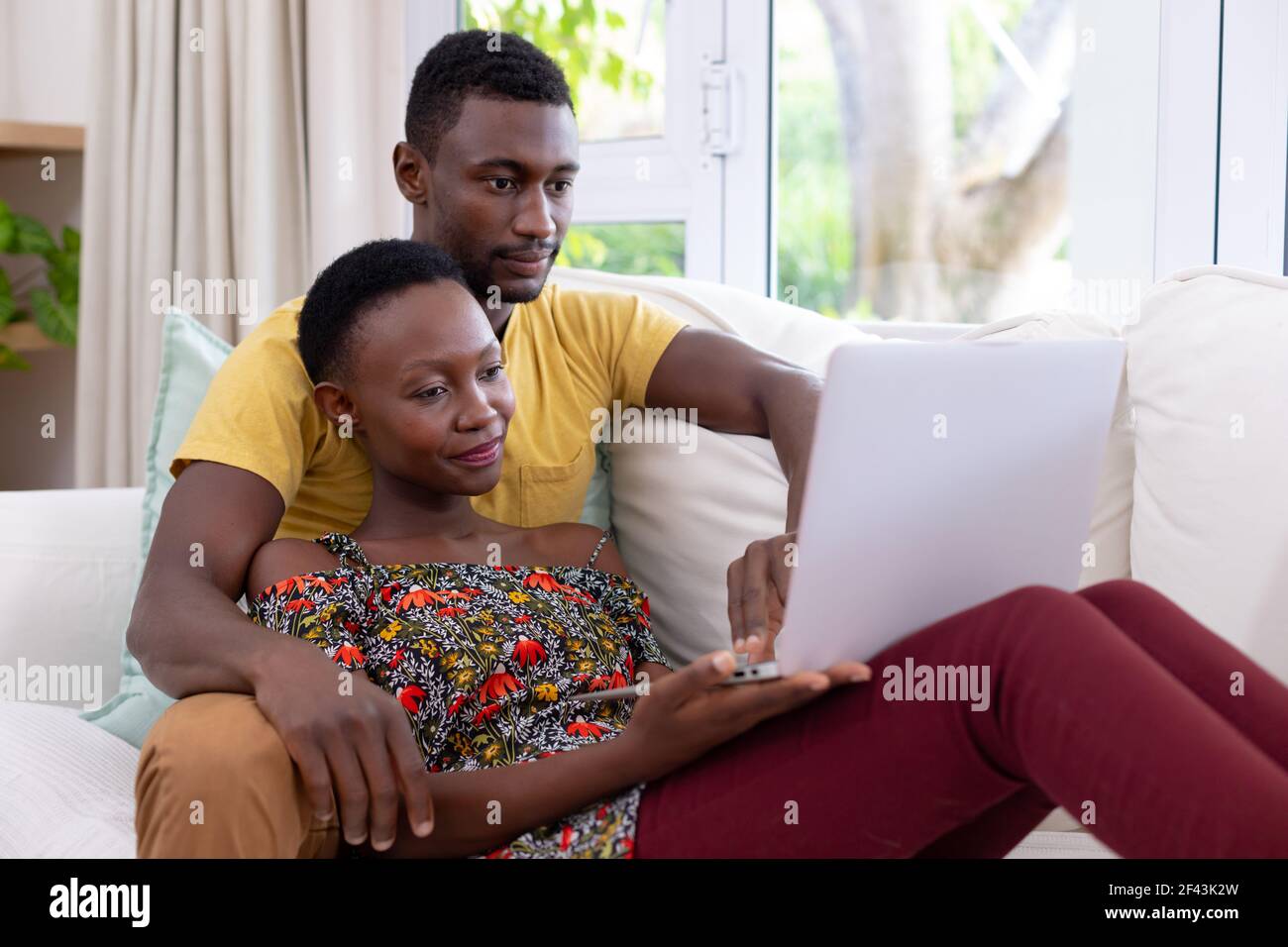 African american couple sitting on sofa using laptop computer and ...