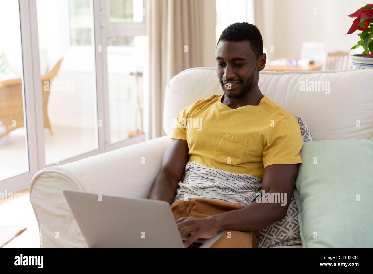 African american man sitting on sofa using laptop computer Stock Photo ...