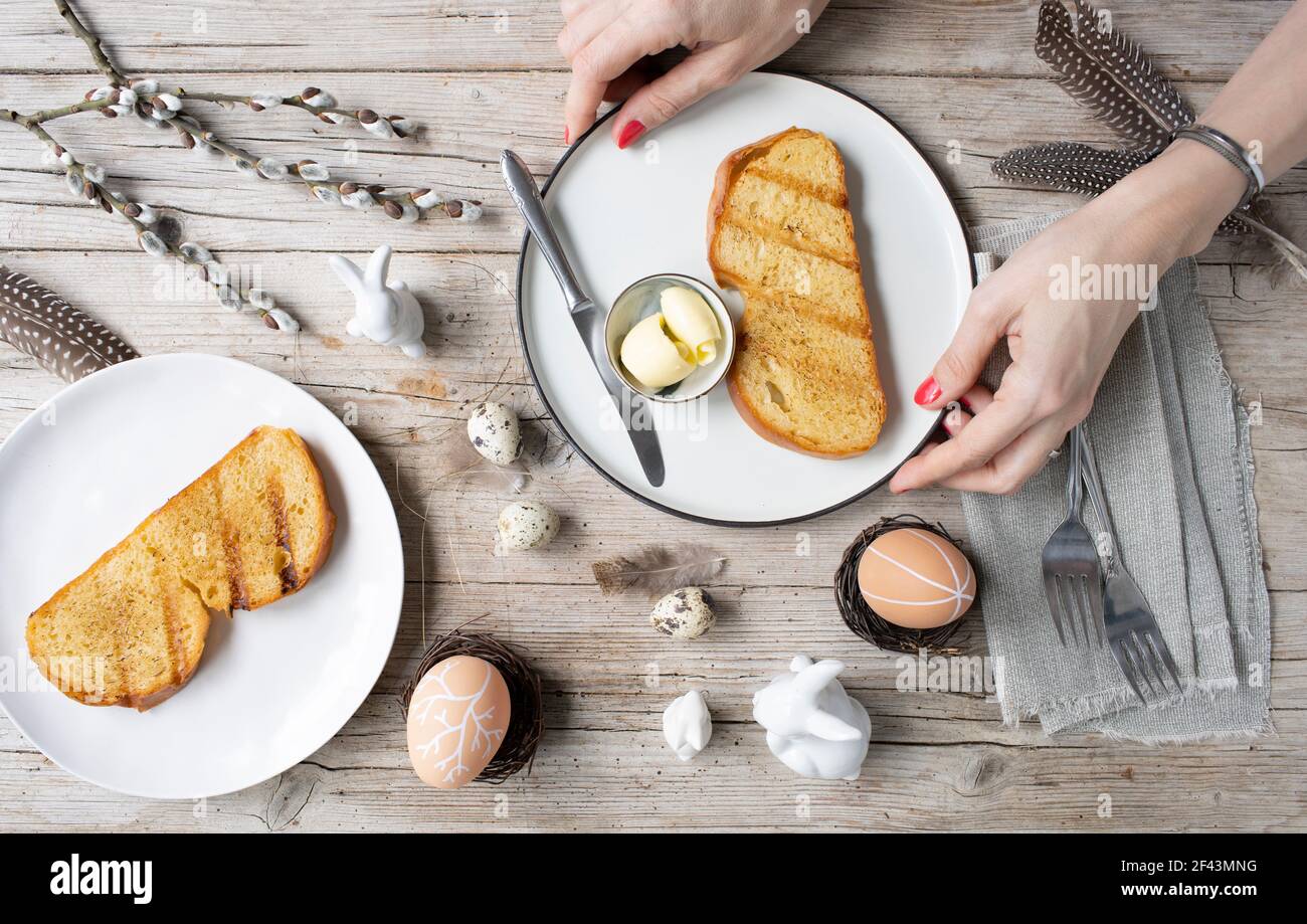 Easter breakfast with golden toasted Easter striezel or also Easter bread with butter with Easter decoration on light wooden background Stock Photo