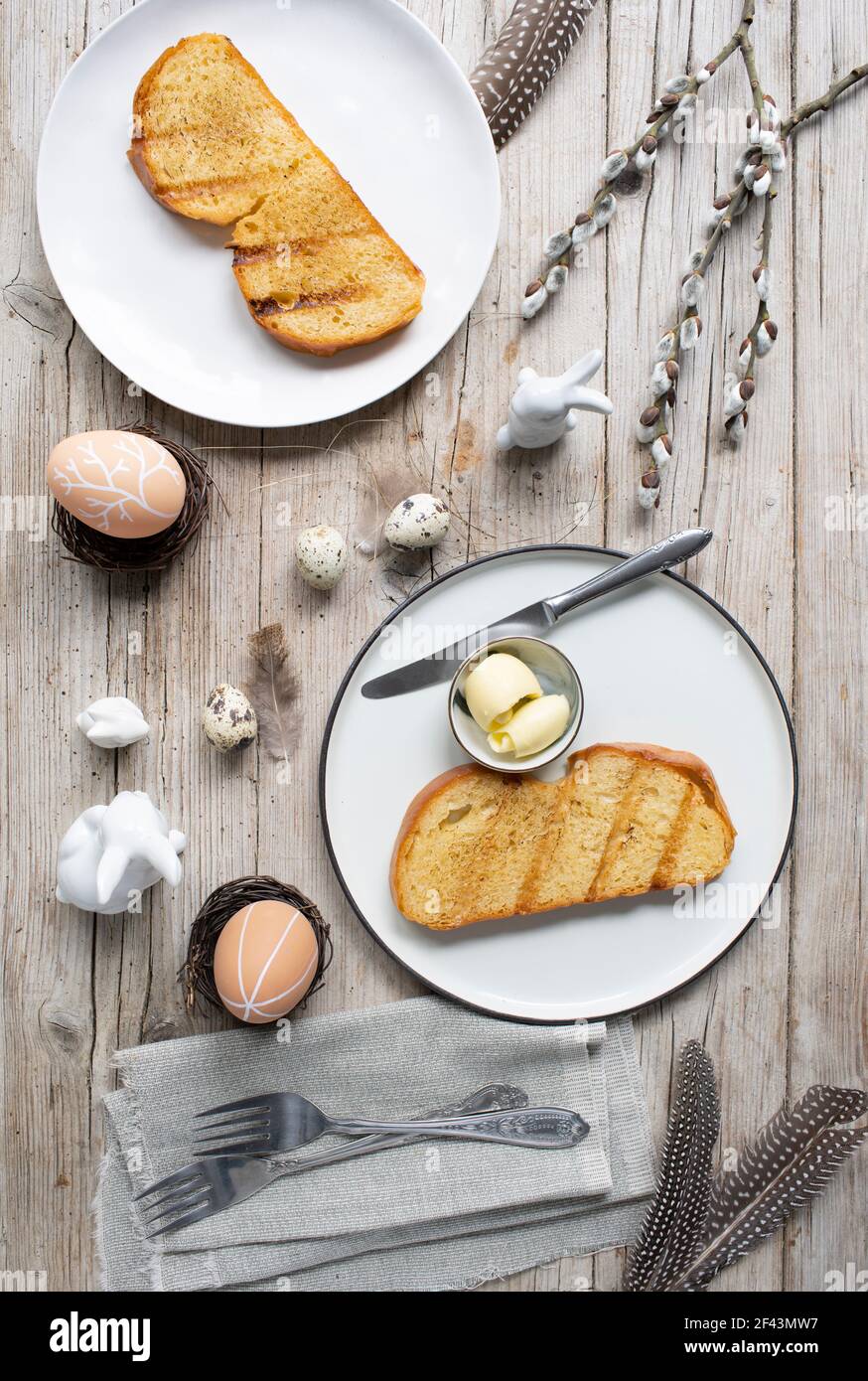 Easter breakfast with golden toasted Easter striezel or also Easter bread with butter with Easter decoration on light wooden background Stock Photo