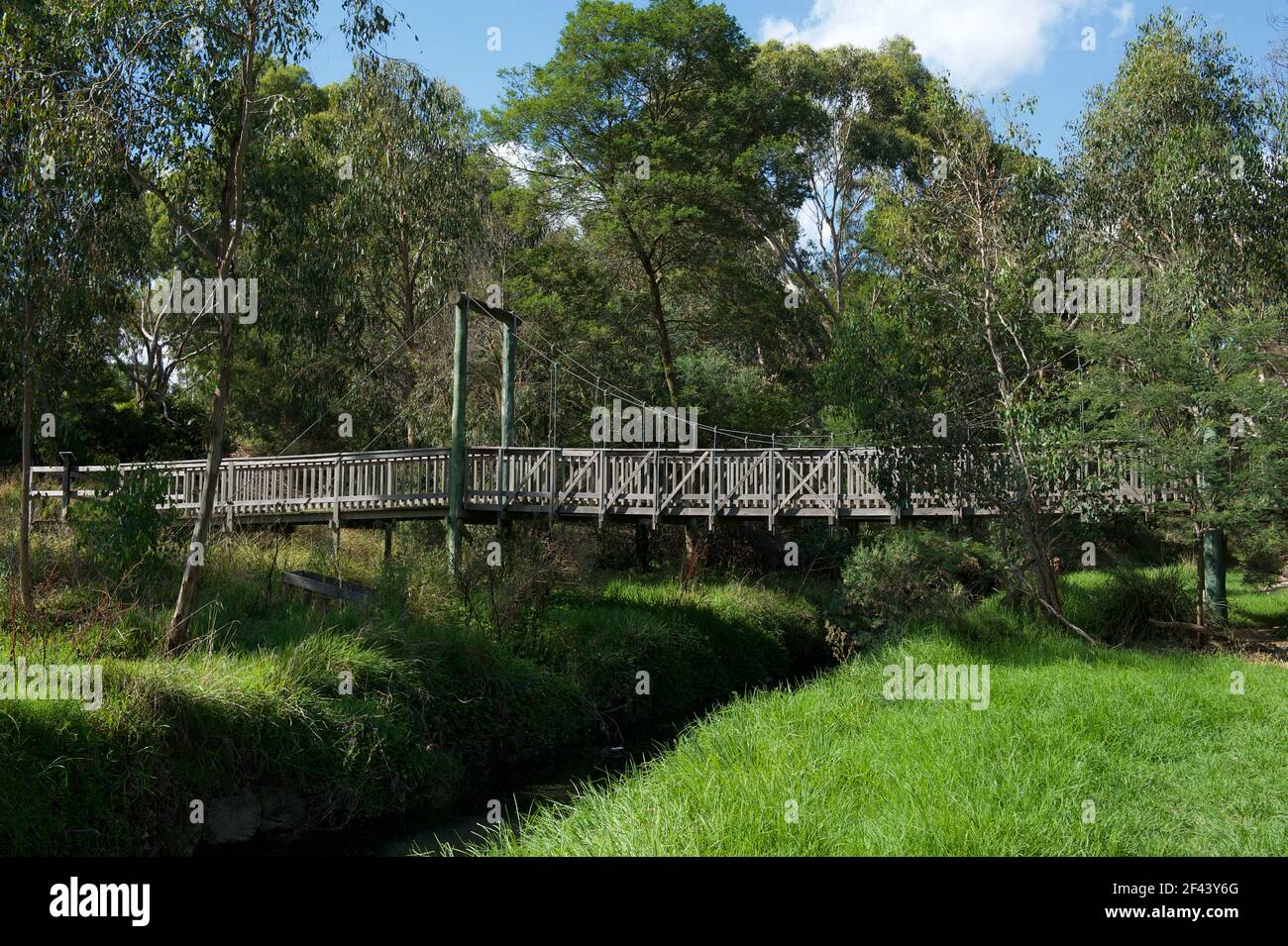 A wooden suspension bridge crosses the Mullum Mullum Creek near Rupert Street in Ringwood, Victoria. All the other timber bridges have been replaced. Stock Photo