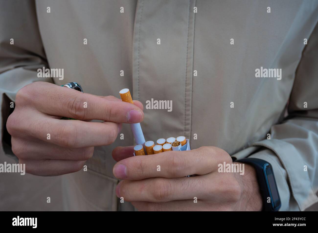 flipping a cigarette hands of a man pulling a cigarette from a cigarette pack. flipped cigarette.  wearing a smart watch. flipped cigarette. ricin Stock Photo
