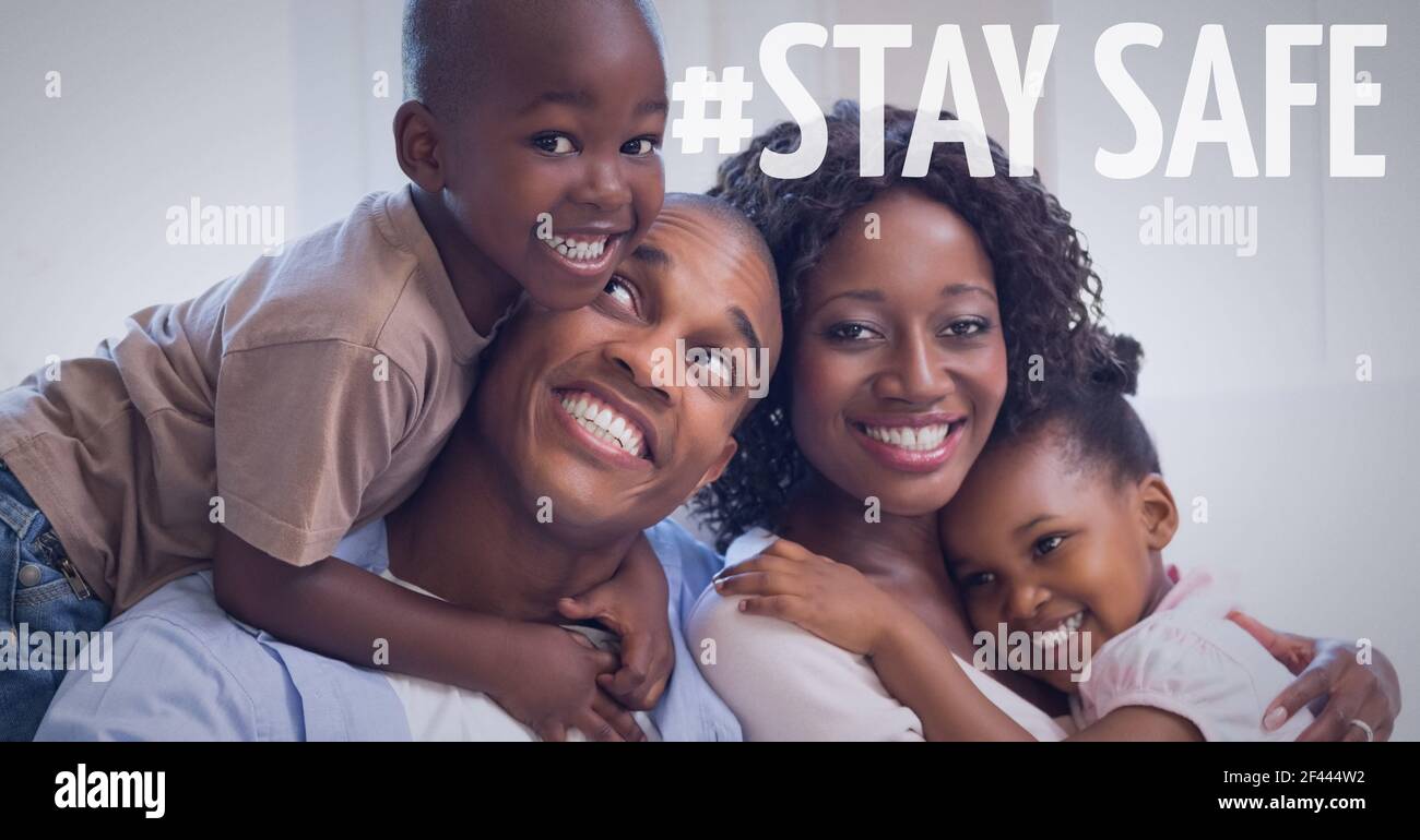 Stay safe text over smiling couple cuddling with their son and daughter at home Stock Photo
