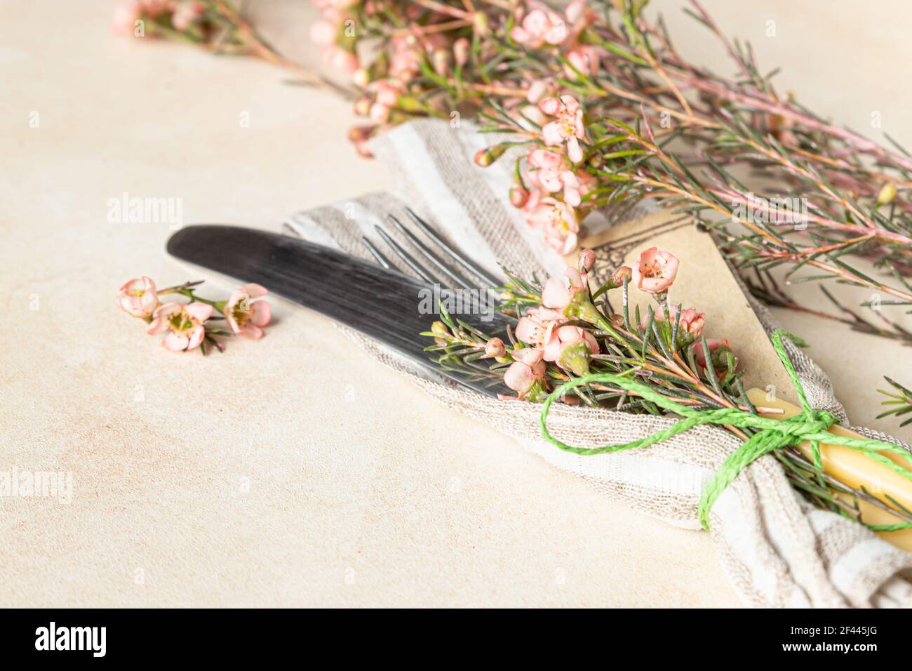 Cutlery set and beautiful pink flowers on light stone table. Easter celebration. Selective focus. Stock Photo
