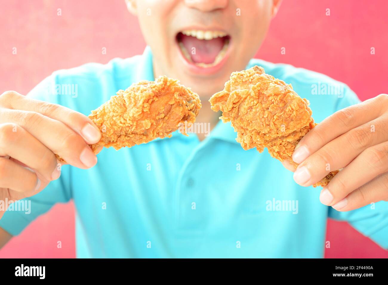 A man with opening mouth about to eat deep fried chicken legs or drumsticks Stock Photo