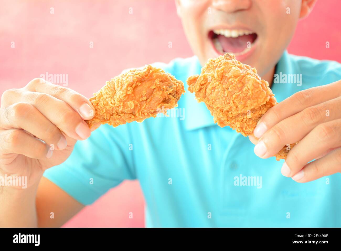 A man with opening mouth about to eat deep fried chicken legs or