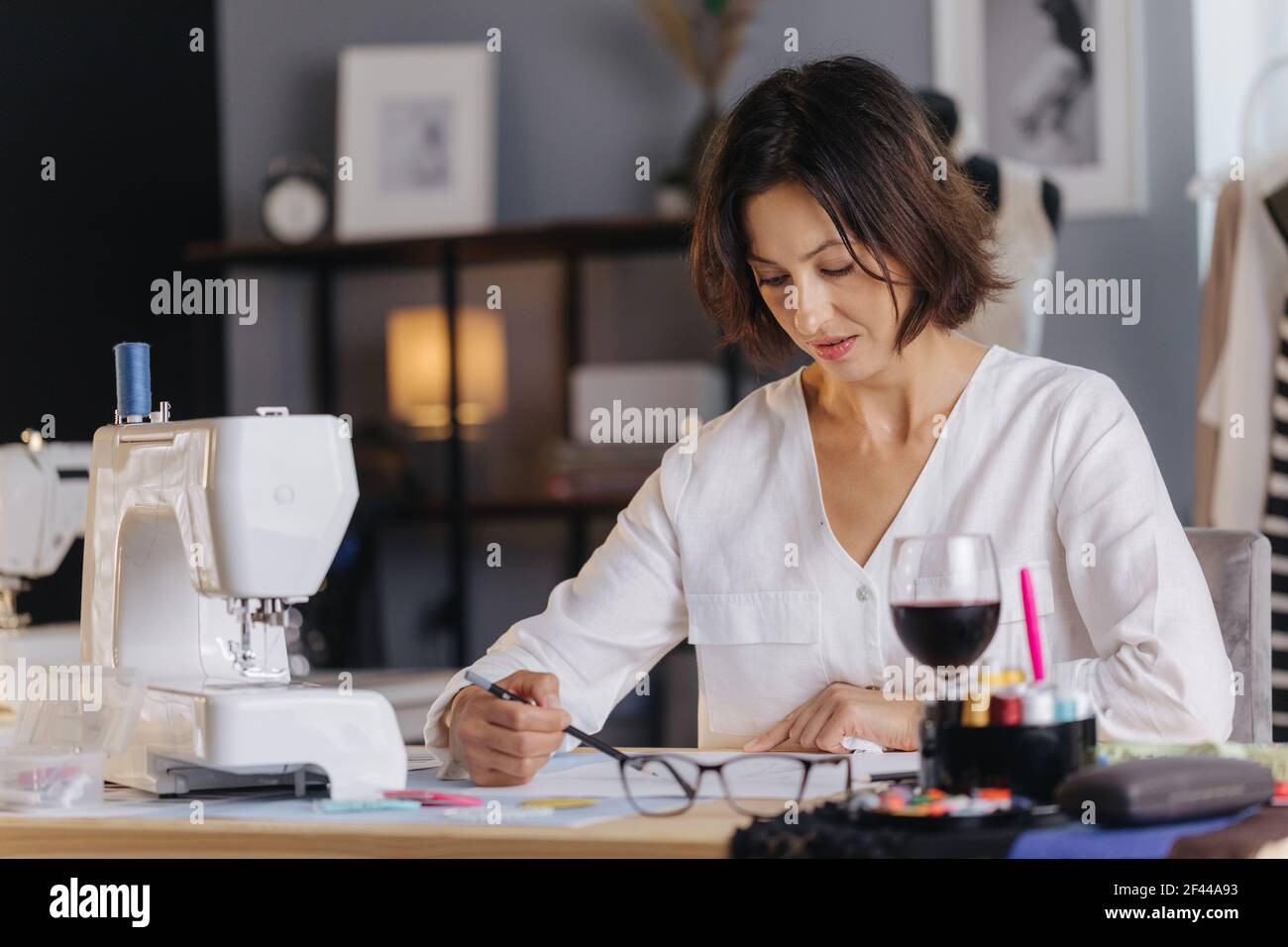 Woman sitting at tailor workshop and sketching Stock Photo - Alamy