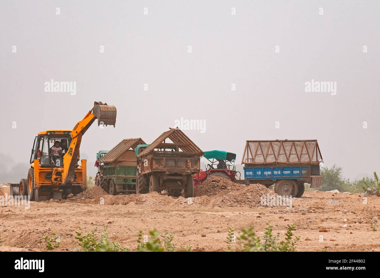 Earthmover loading sand in tractor trolleys illegal mining sand on River Banas, Ranthambore National Park, Wildlife Sanctuary, Ranthambhore, Sawai Madhopur, Rajasthan, India, Asia Stock Photo