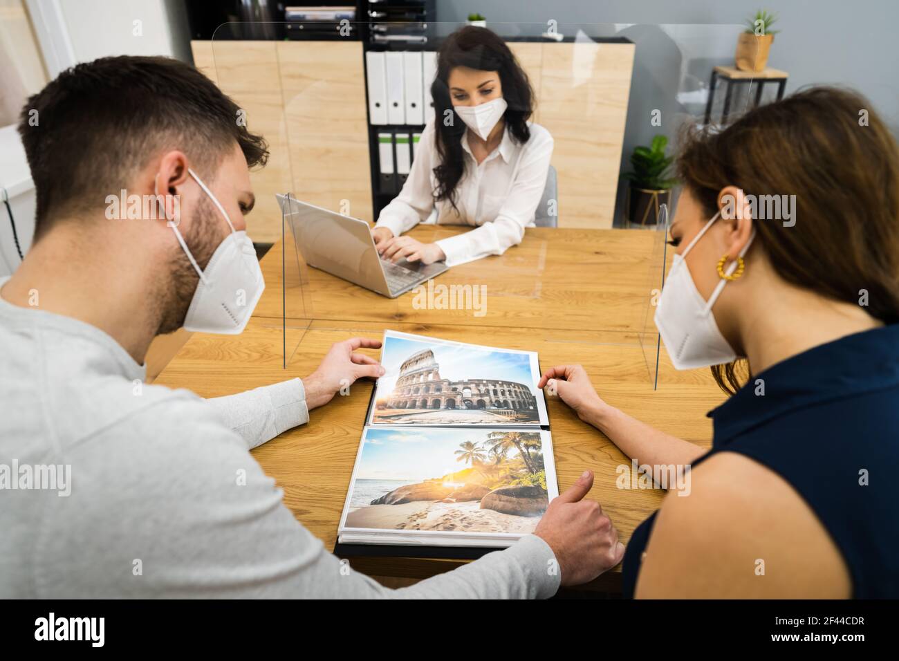 Young Couple With Travel Agent Wearing Face Mask Stock Photo