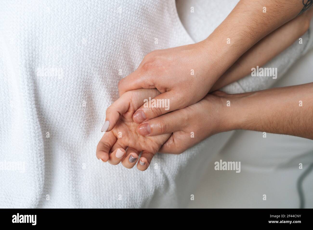 Close-up of male masseur doing finger and palm massage to woman lying on massage table Stock Photo