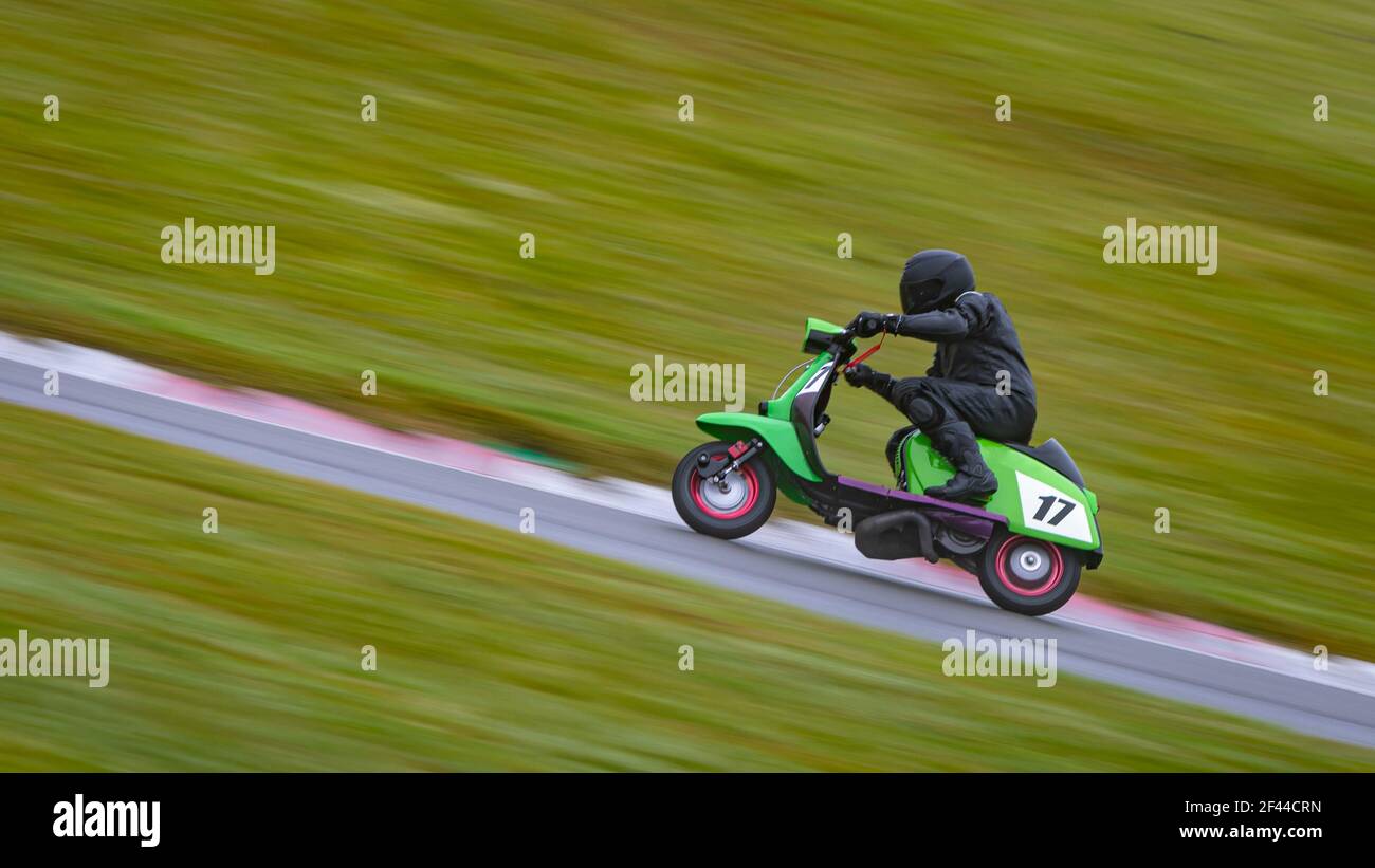 A panning shot of a racing moped as it circuits a track. Stock Photo