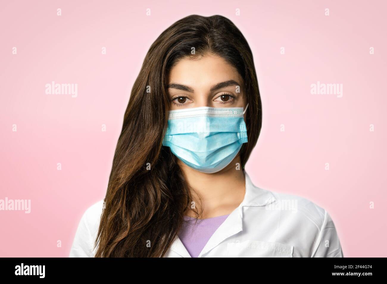 A scientific researcher in a surgical gown and mask. In a pink background. Perfect shot for pandemic, research, vaccine and security. Stock Photo