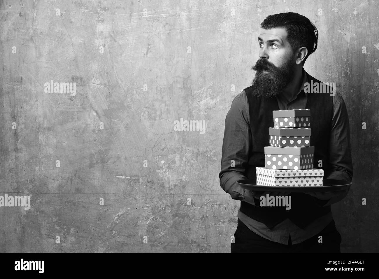 Man with beard holds boxes on beige wall background Stock Photo