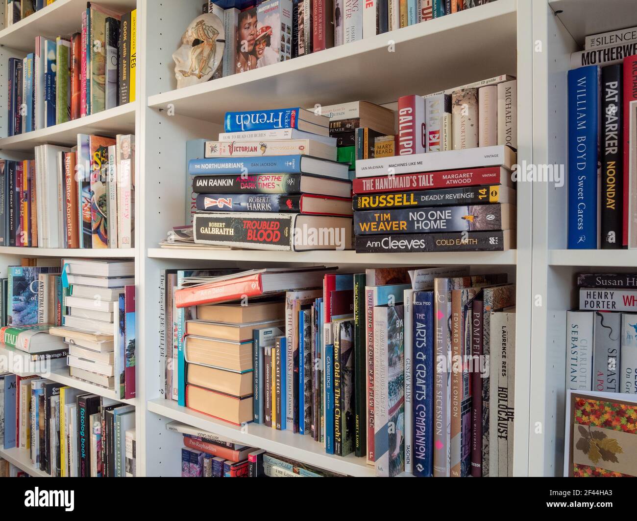 Well filled white wooden bookshelves in a home library, UK Stock Photo