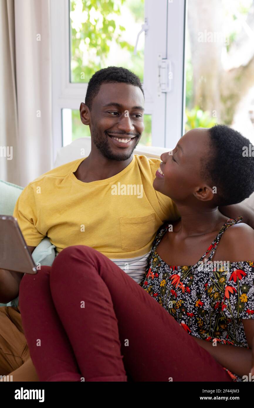 African american couple sitting on sofa using tablet and smiling Stock ...