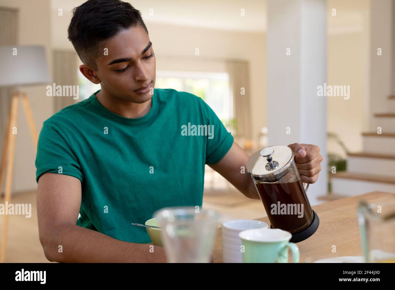 Mixed race man sitting at table and eating breakfast Stock Photo