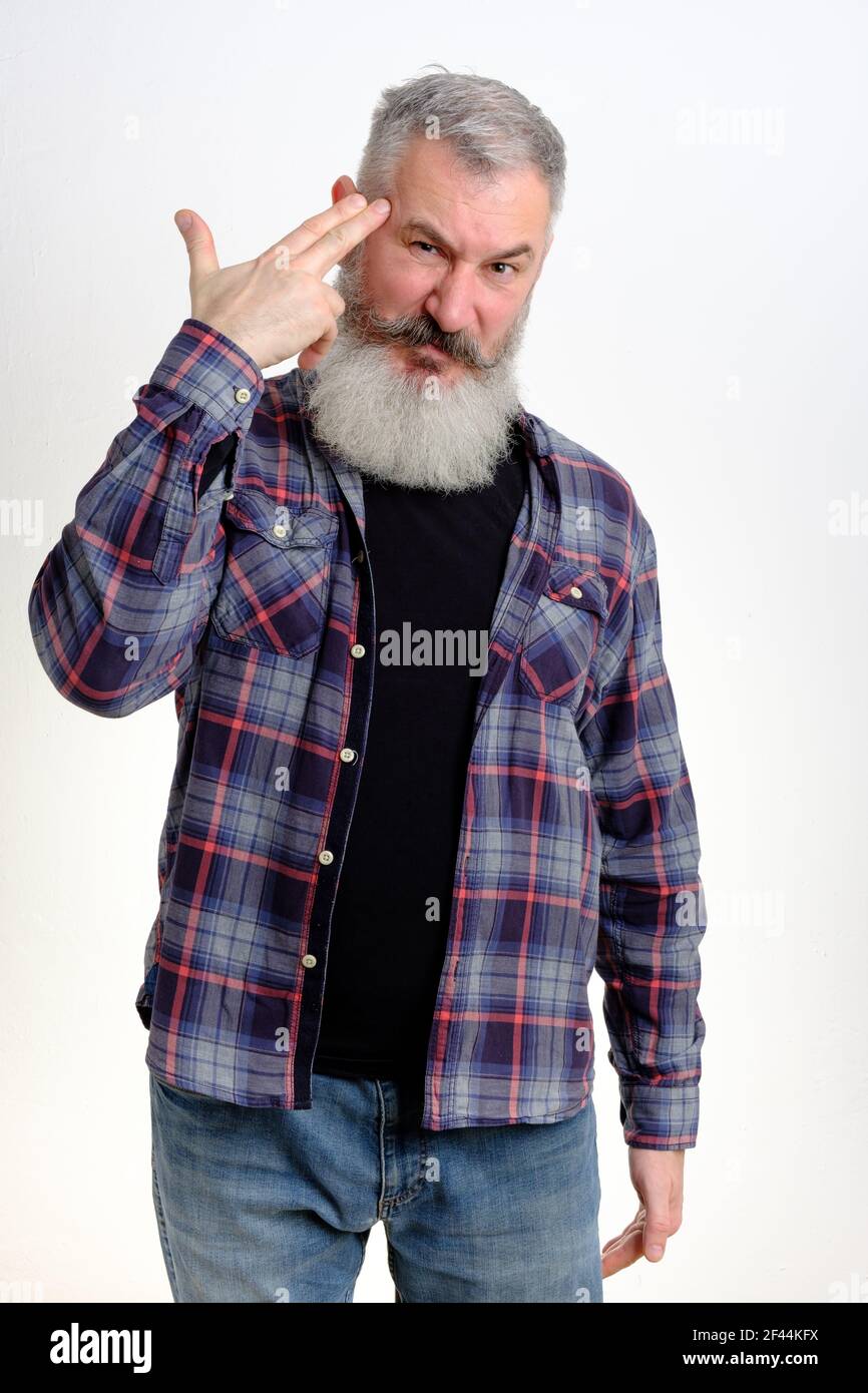 Studio portrait of mature bearded man pointing finger gun gesture to head. Suicide gesture. Isolated on white background. Stock Photo