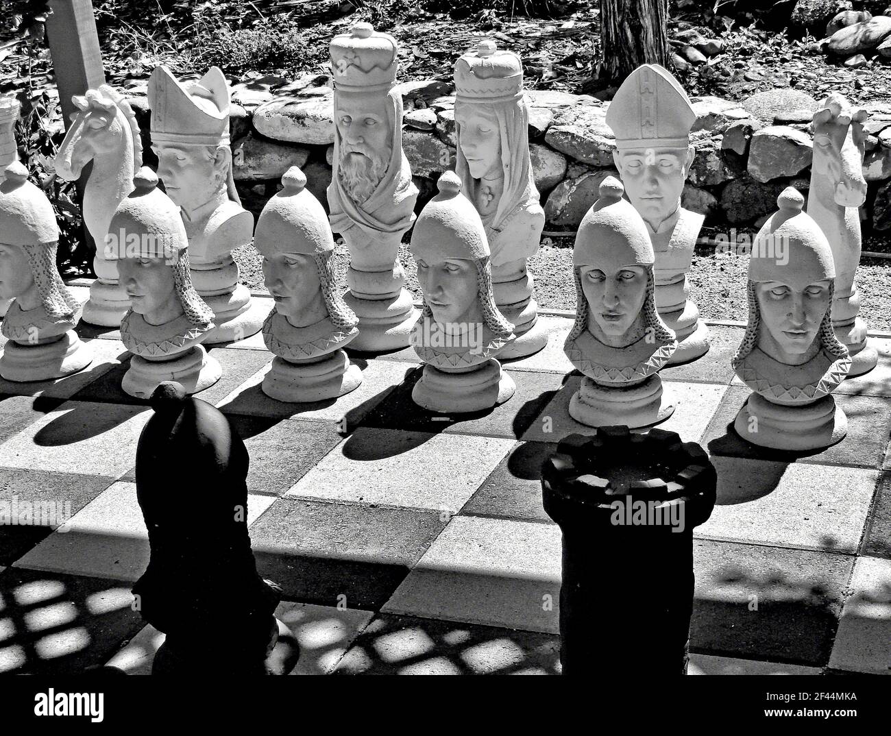 A monochrome closeup shot of white chess pieces with human figures under the sun Stock Photo
