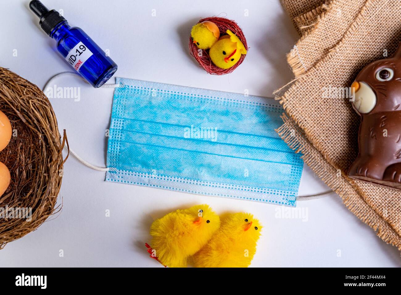 covid19 easter and concept. flat lay with face mask and covid vaccine with easter symbols like easter eggs and chocolate bunny Stock Photo