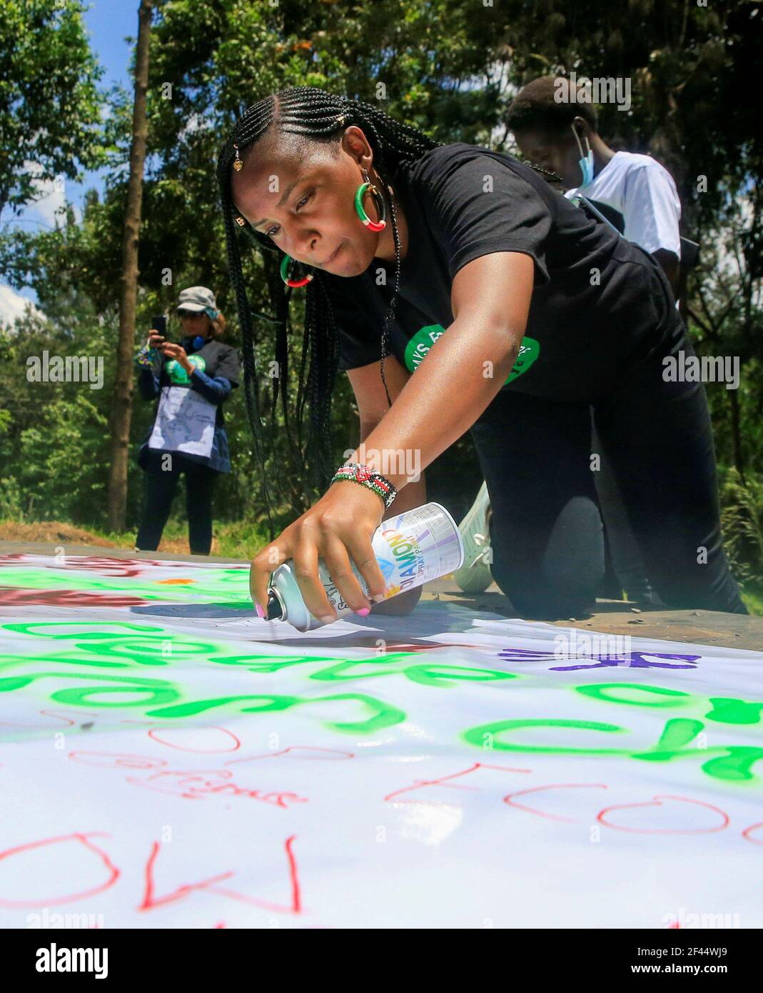 Kenyan environmentalist Elizabeth Wathuti spray paints on a banner as she and the other Fridays For Future activists participate in a protest demanding actions on climate change, at the John Michuki Memorial Park in Nairobi, Kenya, March 19, 2021. REUTERS/Thomas Mukoya Stock Photo