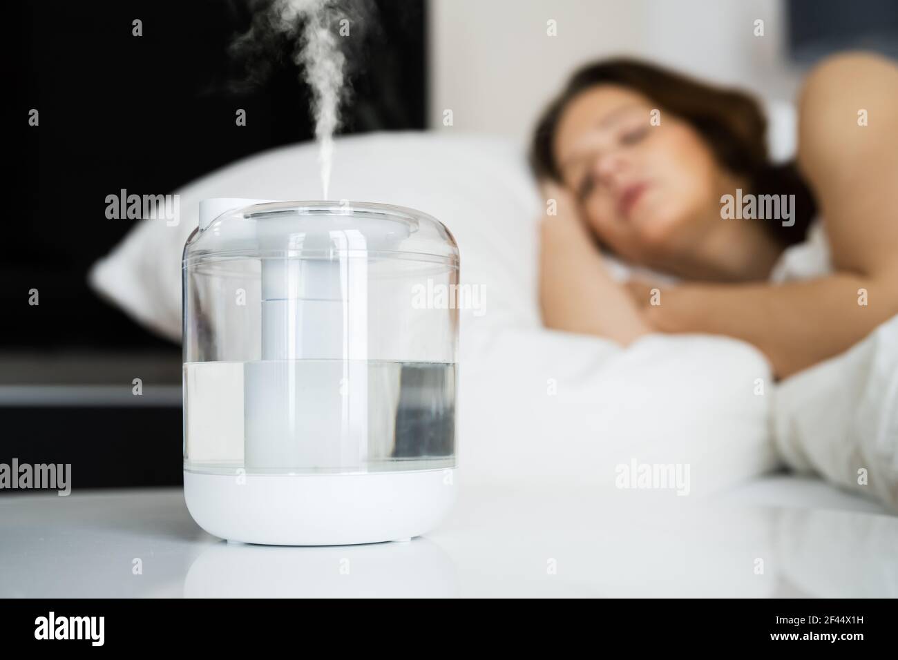 Home Air Humidifier Device In Bedroom Near Woman Sleeping Stock Photo