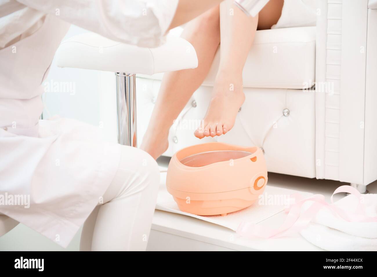 Wax bath for feet at beauty spa salon. Paraffin wax treatments for feet. Stock Photo