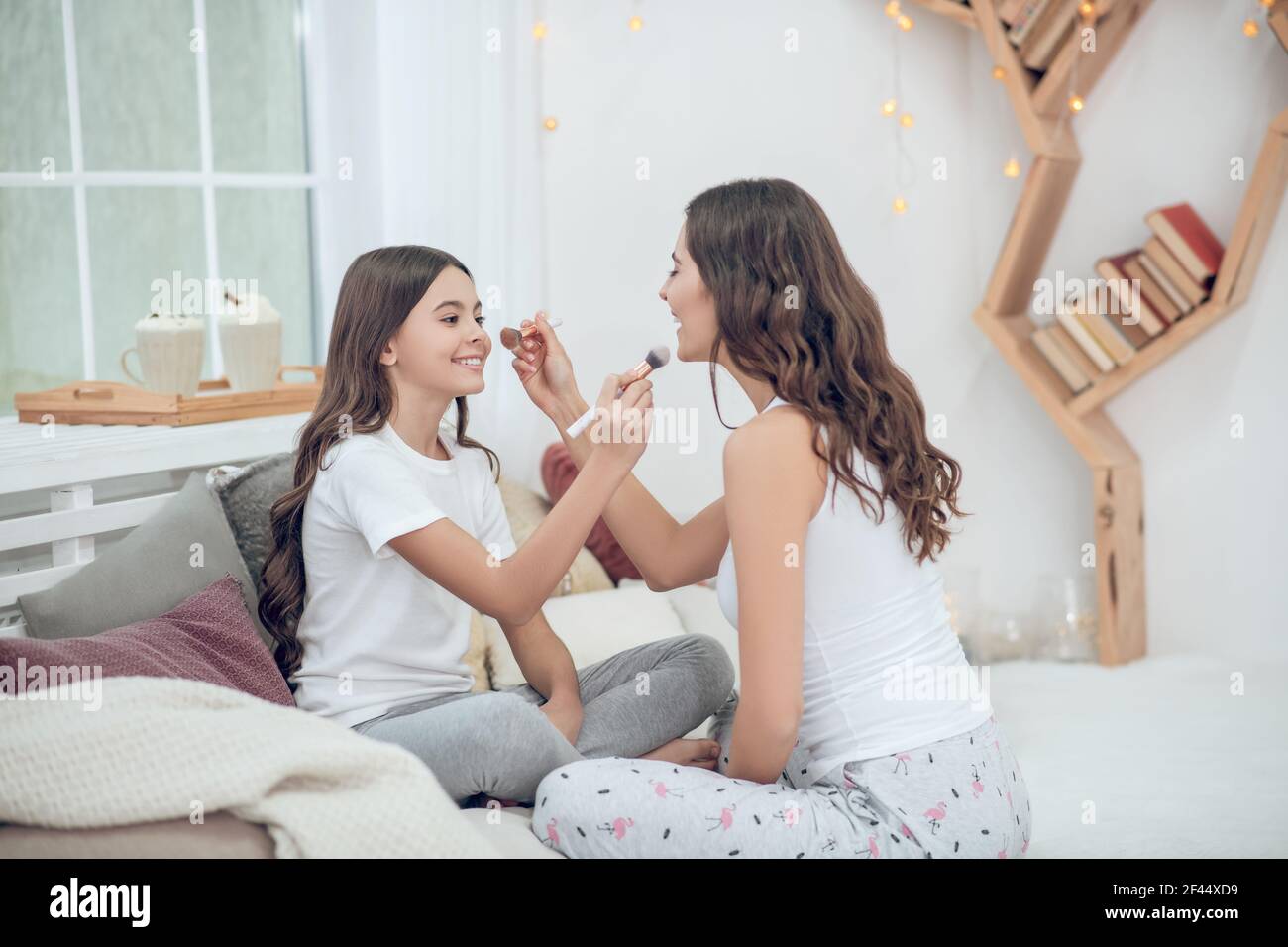 Mom and daughter with brushes sitting opposite each other Stock Photo