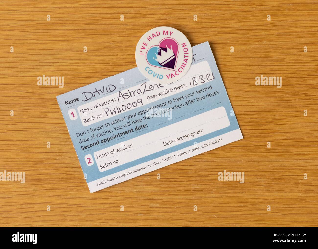 COVID 19 vaccination card and sticker, issued to people who have had their first injection. Bishop's Stortford, Hertfordshire. UK Stock Photo