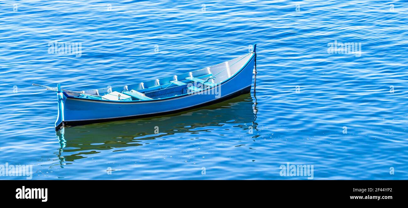 An empty blue boat in the blue water of a lake Stock Photo - Alamy