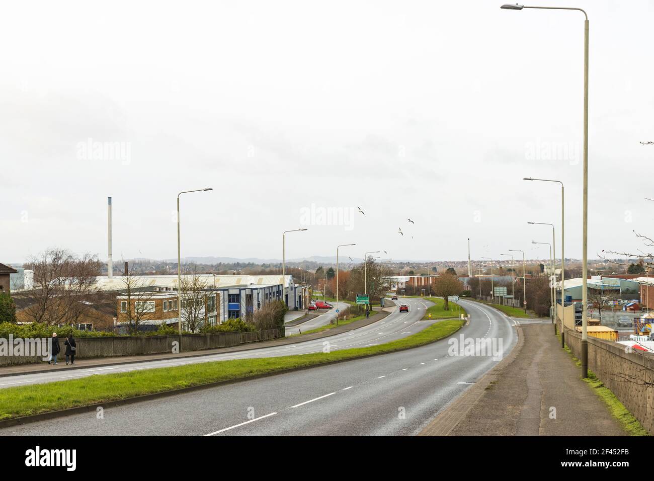 Main road junction on Thurmaston Road A563, roundabout, lamp posts and industrial units. Charnwood Forest and Old John Tower in distance. Stock Photo