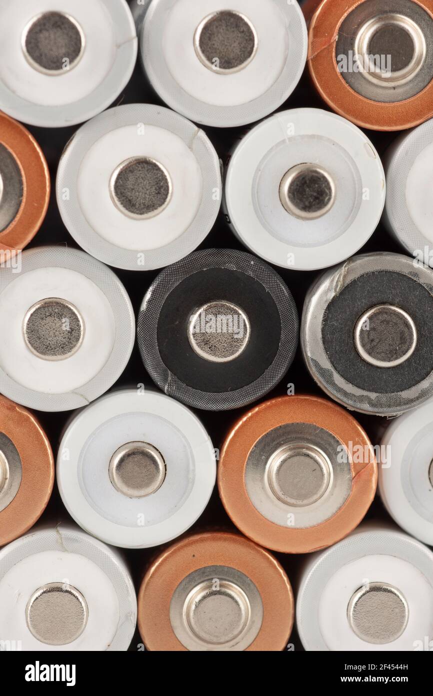 Pile of old white, black and golden AA batteries showing positive end