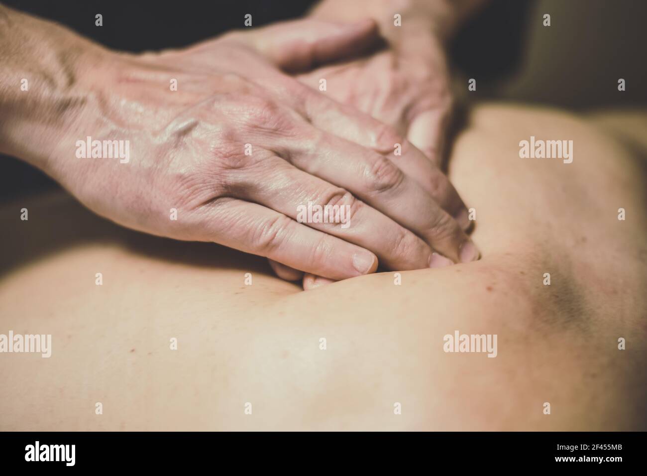 Masseur massaging back of female with oiled hands Stock Photo. 