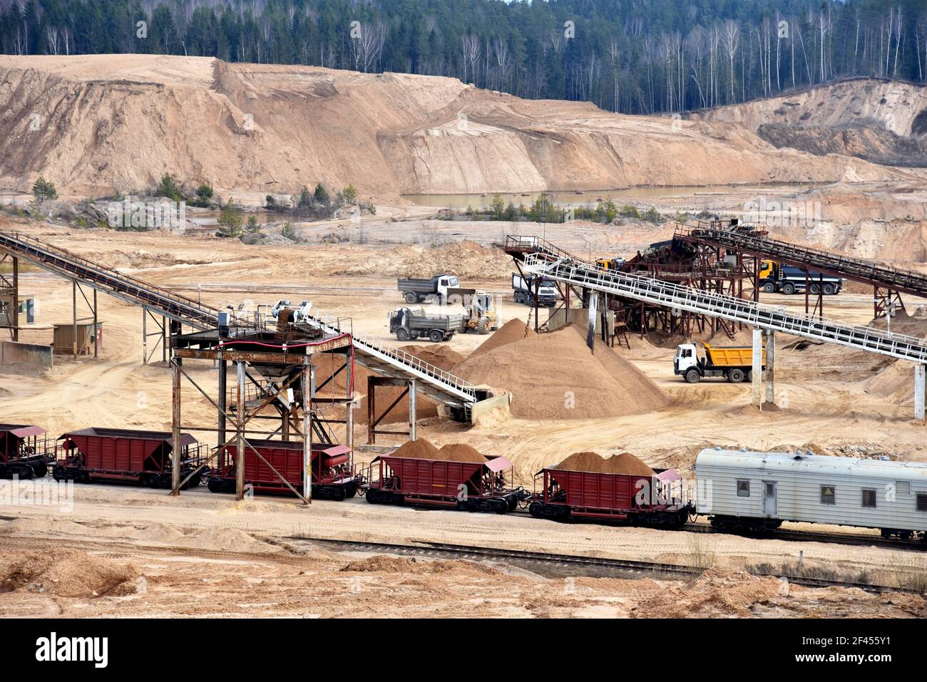 Loading sand into freight cars of a train in quarry. Sand Making Plant in open-pit mining. Crushing factory, machines and equipment for crushing, grin Stock Photo