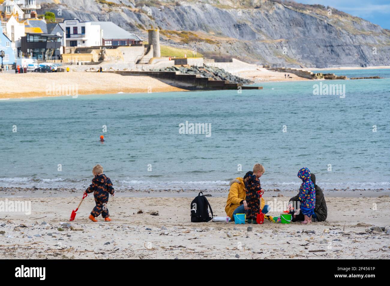 Lyme Regis, Dorset, UK. 19th Mar, 2021. UK Weather: A mixed bag of sunshine and cloud along with a chilly breeze at the seaside resort of Lyme Regis. A family enjoyed having the beach to themselves as the bracing sea breeze kept people away. Unsettled conditions are forecast over the weekend Credit: Celia McMahon/Alamy Live News Stock Photo