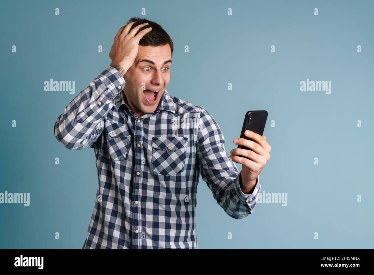 Handsome young man using mobile phone isolated over blue backround Stock Photo