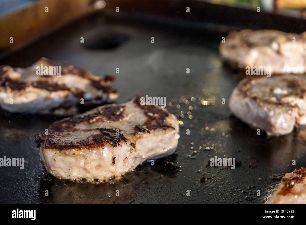 Marinated boneless pork chops cooking on a hibachi style outdoor large