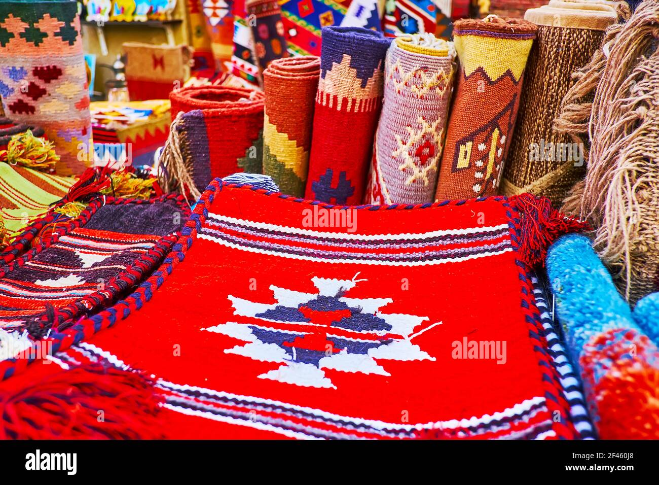The carpet rolls, rugs and pillow cases, decorated with colored tribal patterns in stall of Al Souk al Kabir (Old Market) in Dubai, UAE Stock Photo