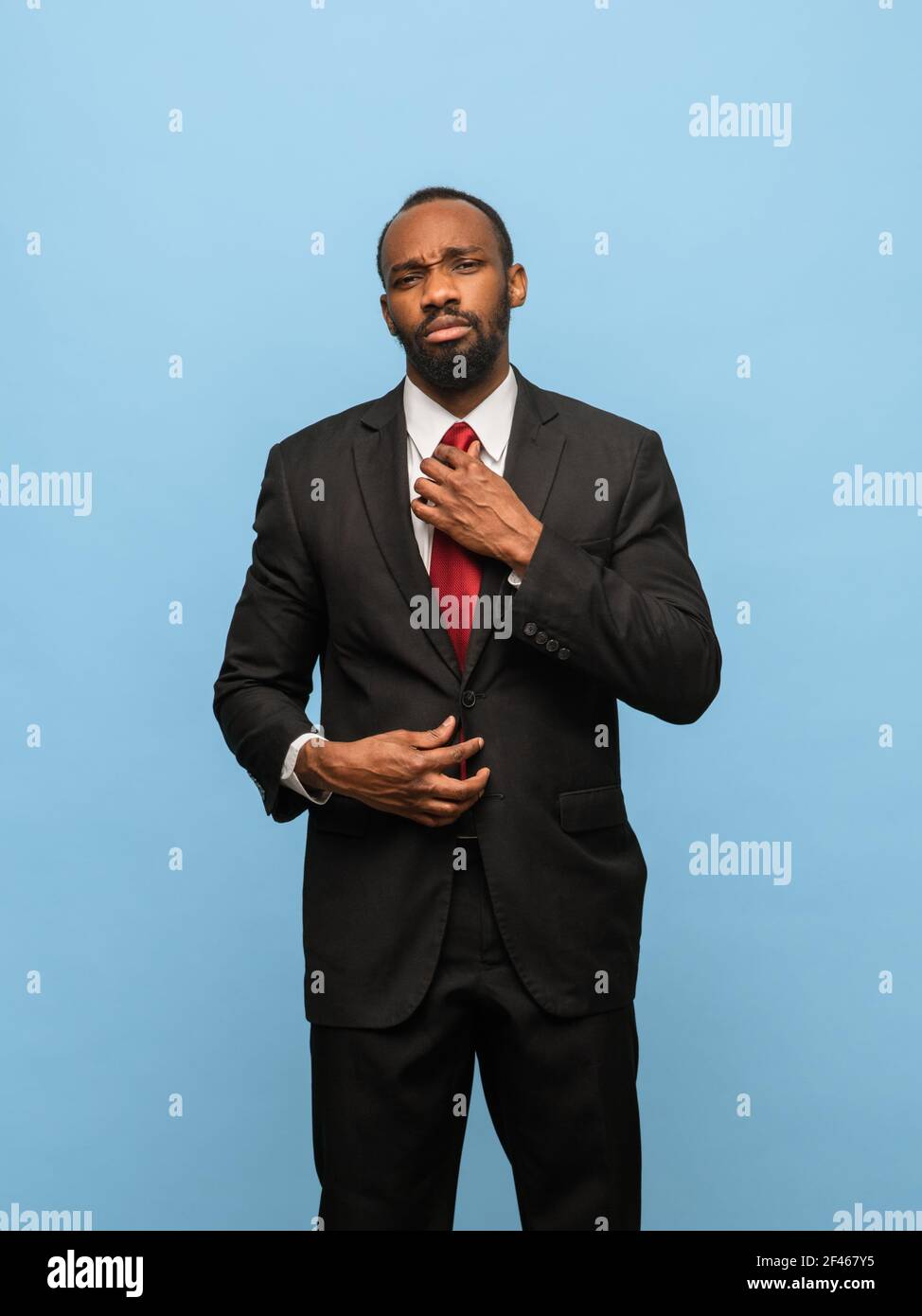 Portrait of young African-American man in black suit isolated on blue ...