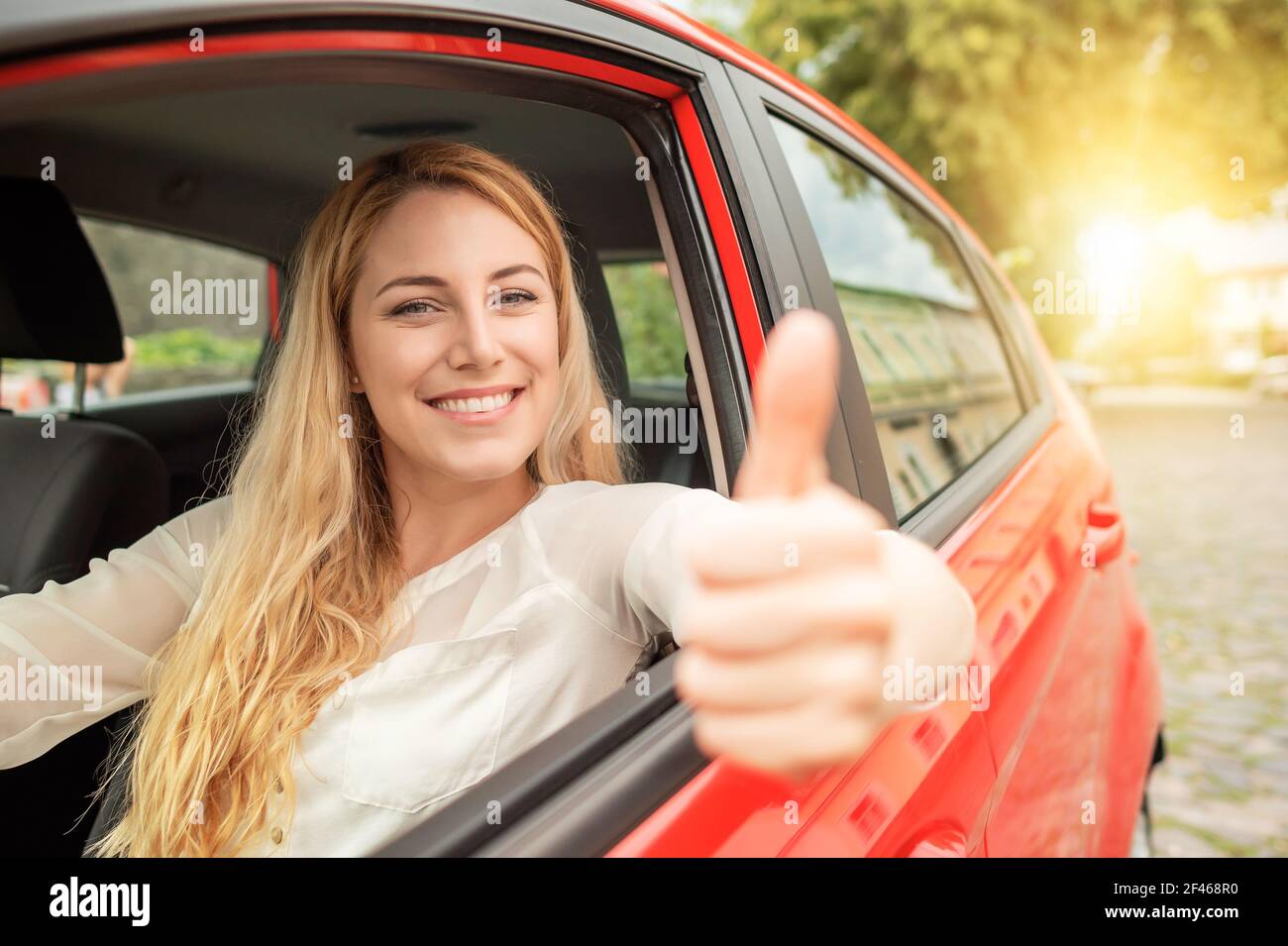 Happy beautiful woman is driving a red car Stock Photo - Alamy