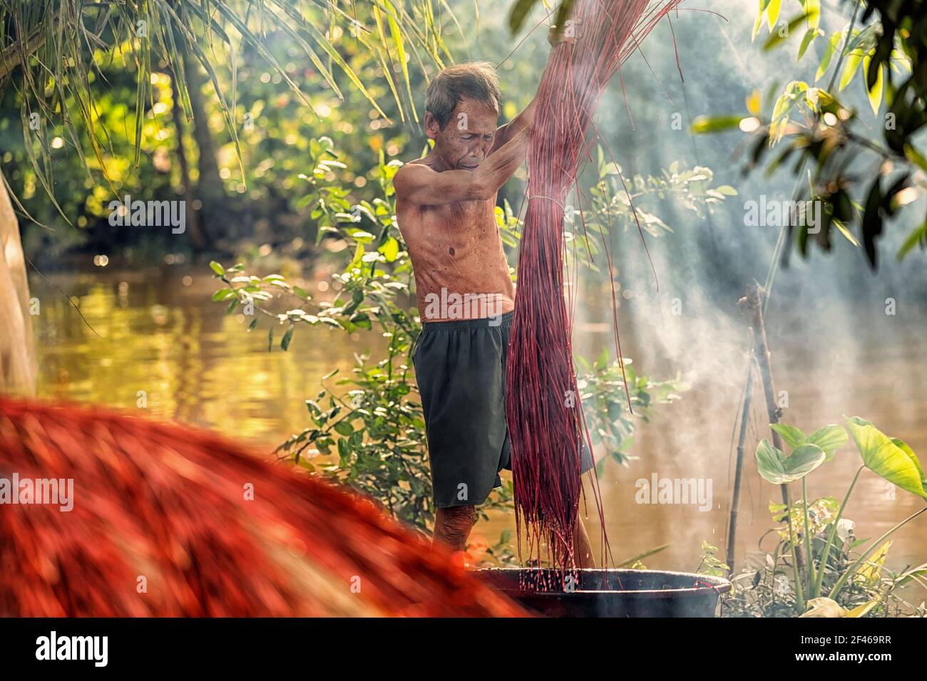 Vietnamese Old man craftsman Dyeing the traditional vietnam mats in the old traditional village at dinh yen, dong thap, vietnam, tradition artist conc Stock Photo