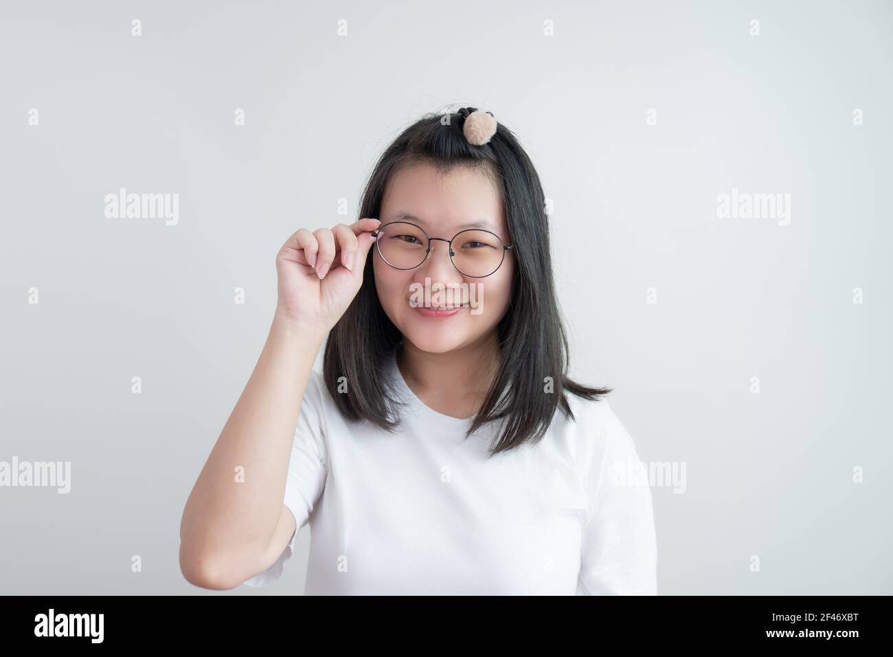 Young Asian Glasses Girl Touches Her Glasses And Smiles To Camera On