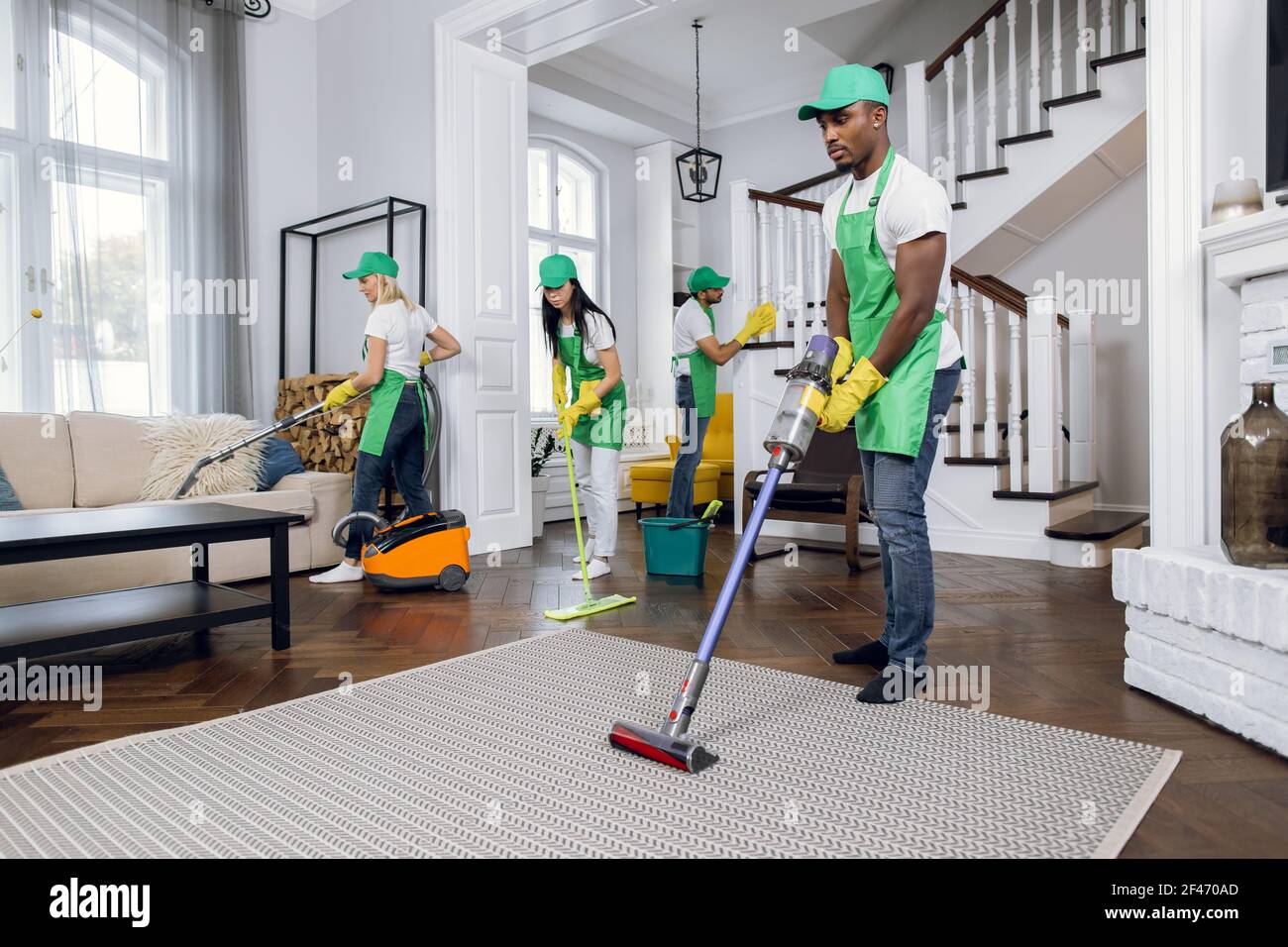 Group of four multiracial people cleaning client house Stock Photo - Alamy