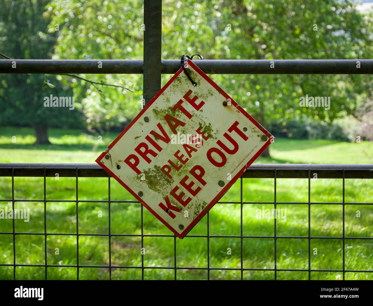 A Private Keep Out sign hanging at a crooked angle on a gate to a field in rural Somerset, England. Stock Photo