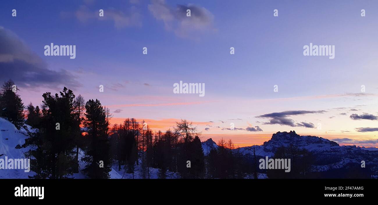 the sun sets on the Dolomites with the colored clouds Stock Photo - Alamy