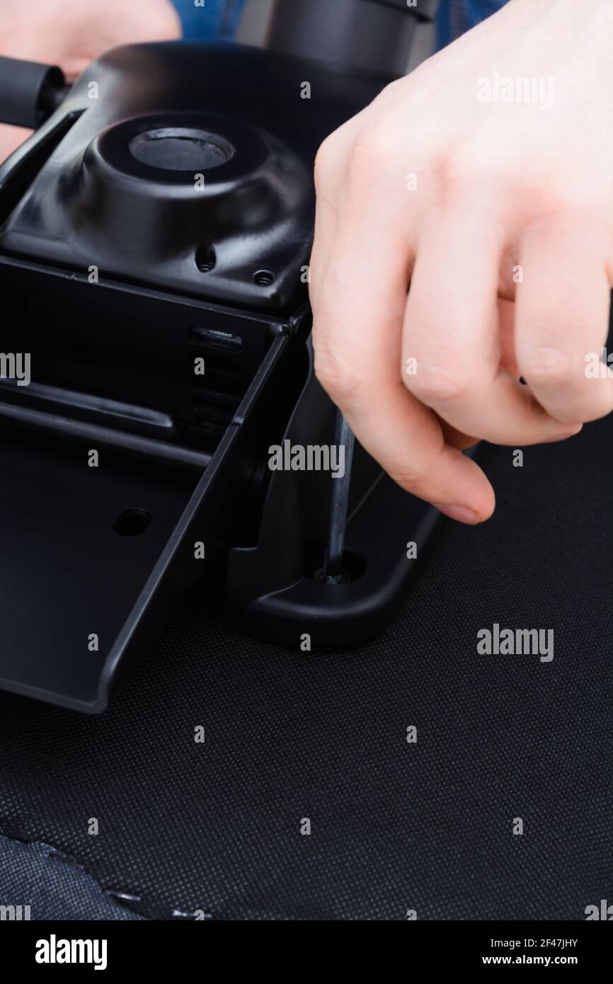 Caucasian man hands screw chair lifting mechanism. Assembling office chair Stock Photo